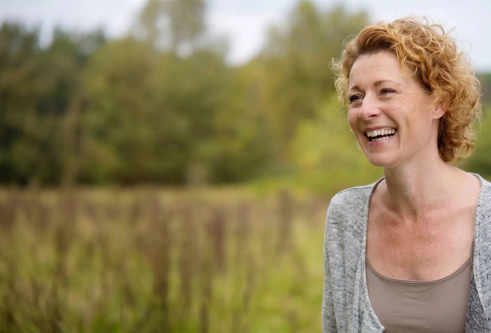 Lachende vrouw in een groen landschap onderweg naar de cursus